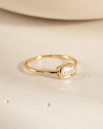side view of gold baguette ring with bezel set stone