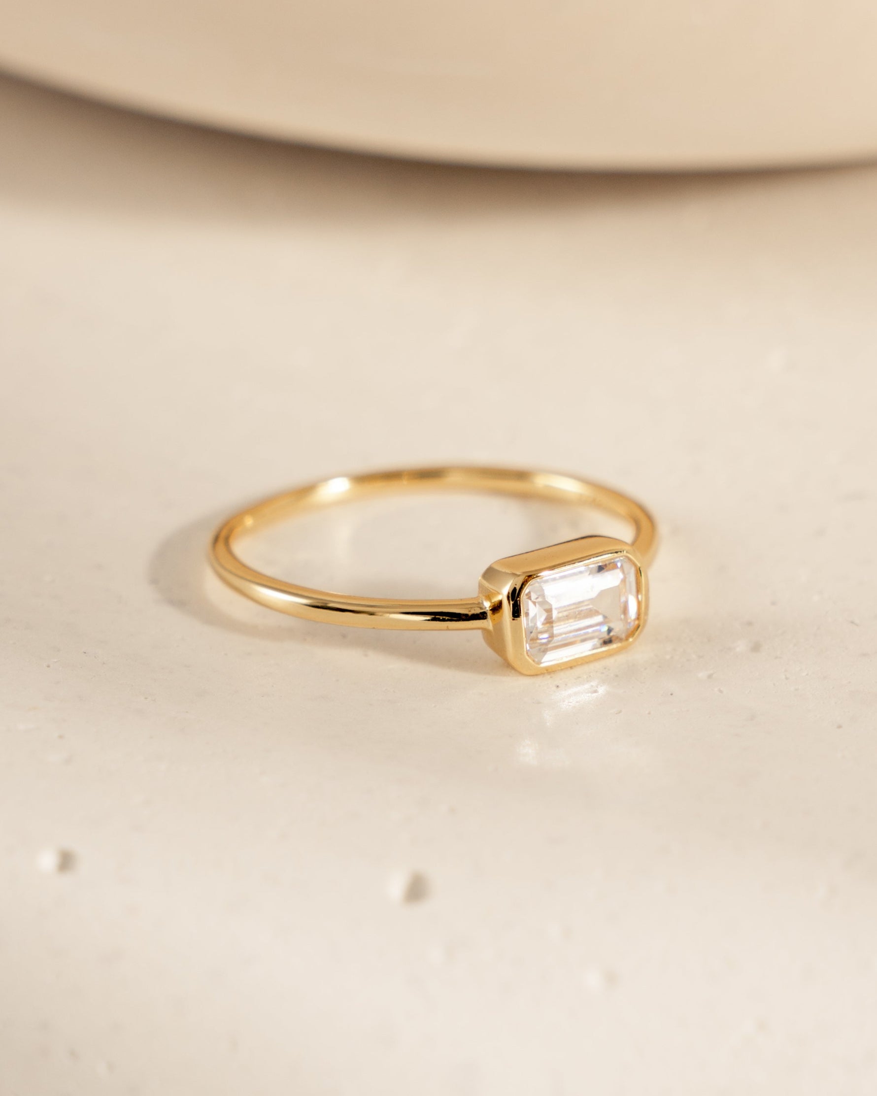 side view of gold baguette ring with bezel set stone