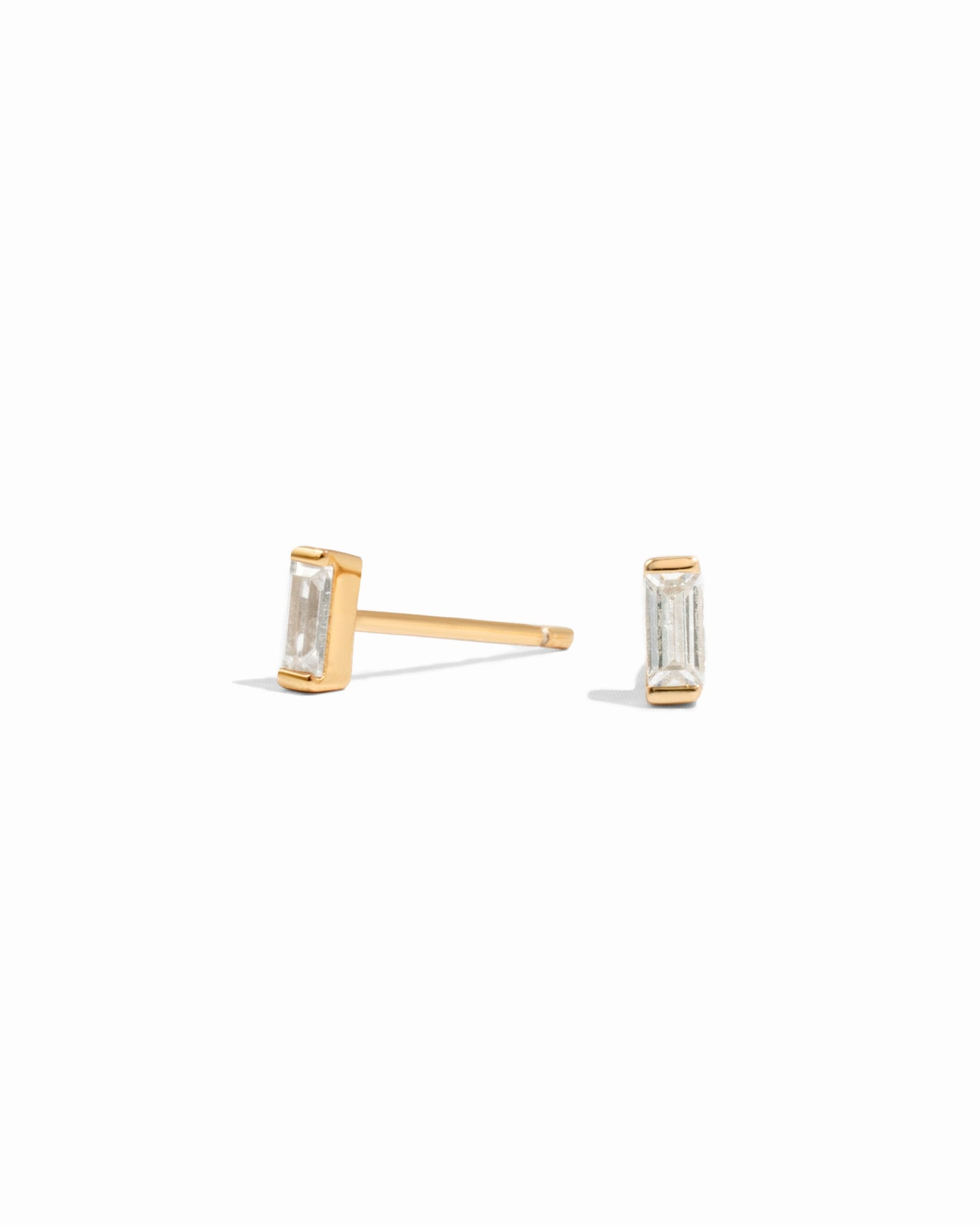 closeup image of minimalist gold earrings on a white background