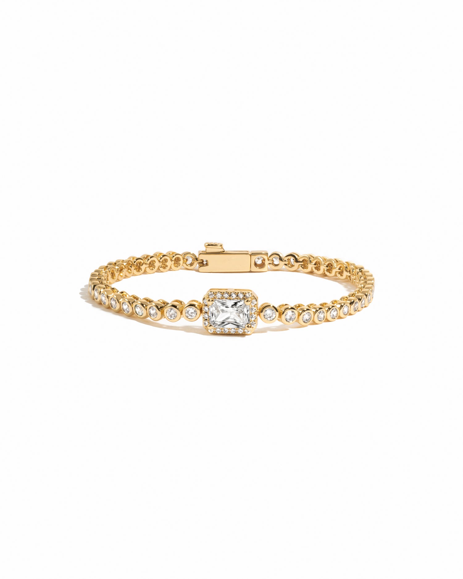 Gold tennis bracelet with a central baguette diamond on a white background