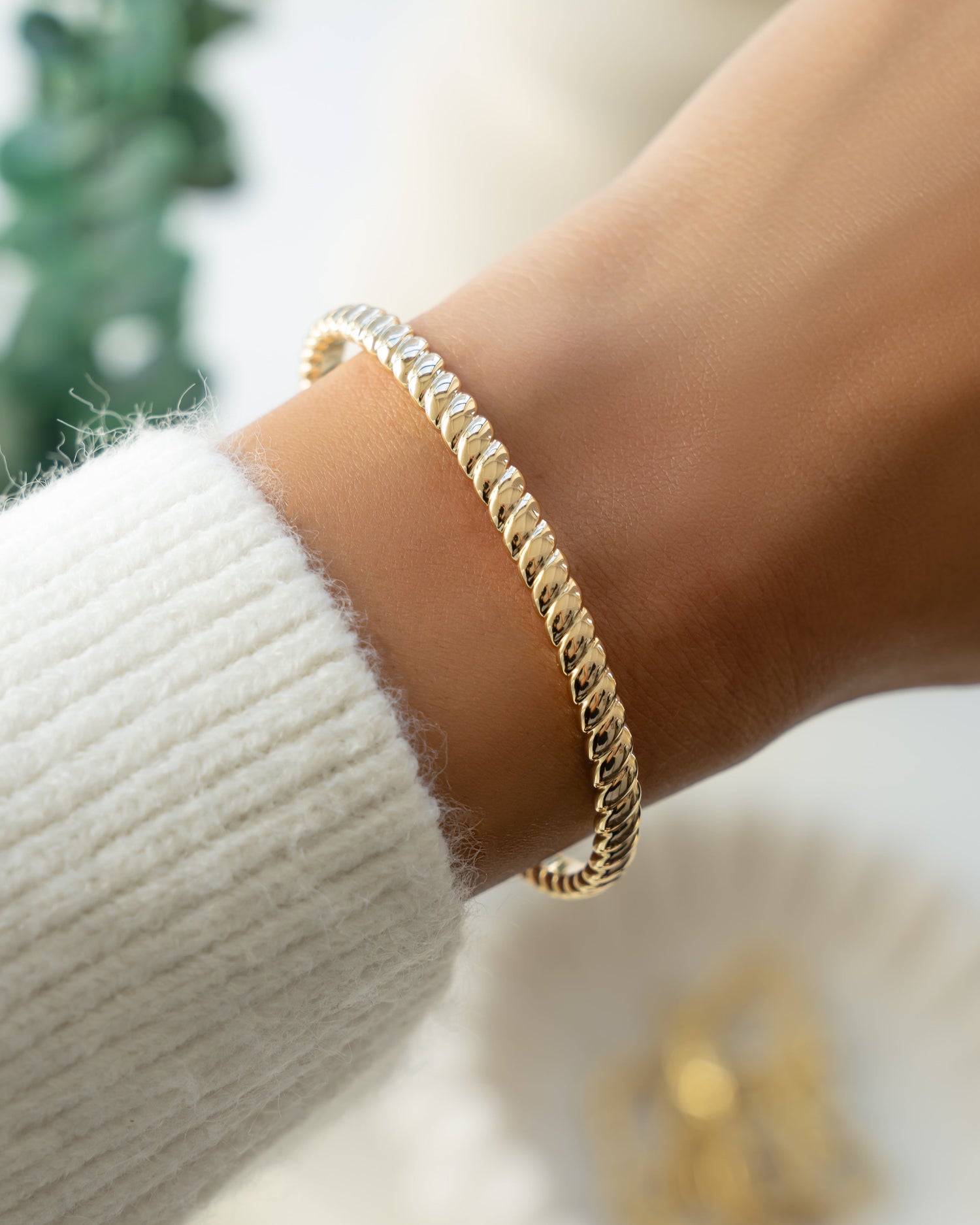 Gold stacking bangle bracelet on models wrist