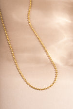 Gold dainty necklace on beige background