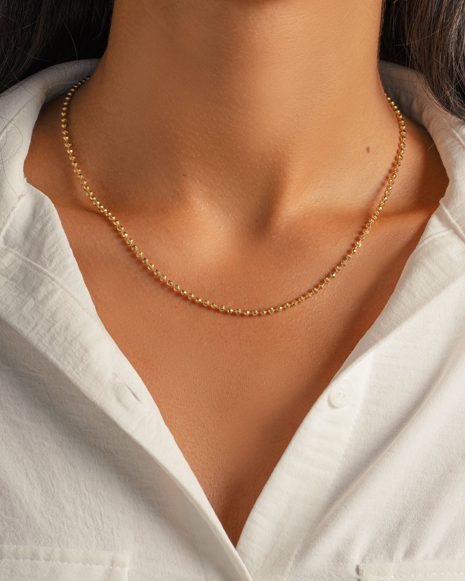 Model wearing gold beaded stacking necklace on model