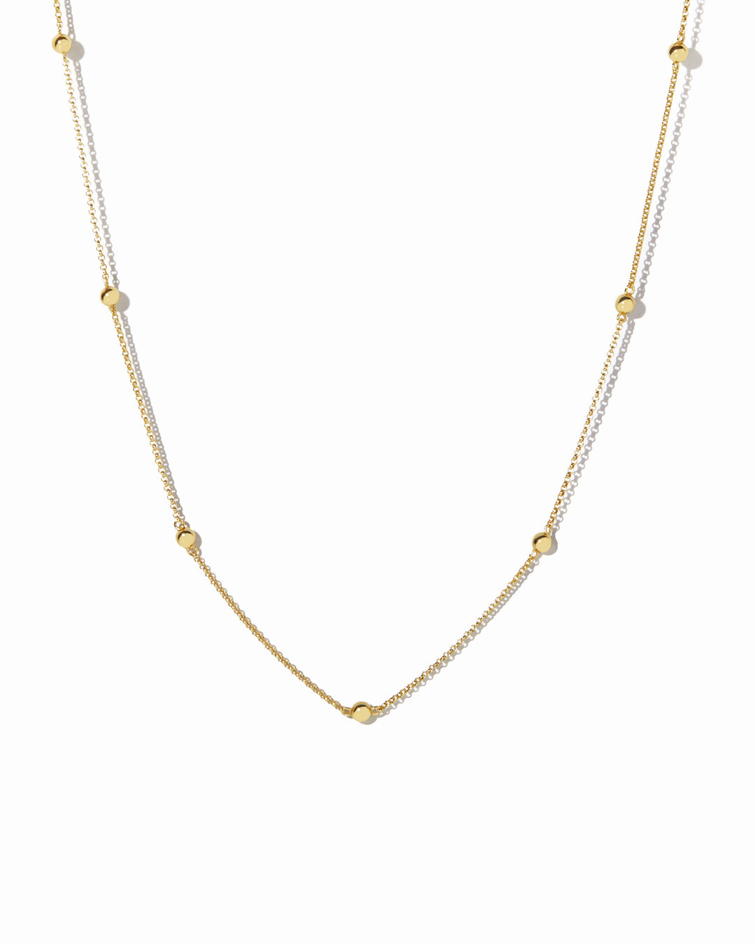 Gold beaded necklace on a white background