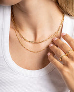 Close-up of a model wearing gold layering necklaces and gold stacking rings 