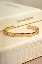 Gold adjustable arm cuff bracelet on decorative book