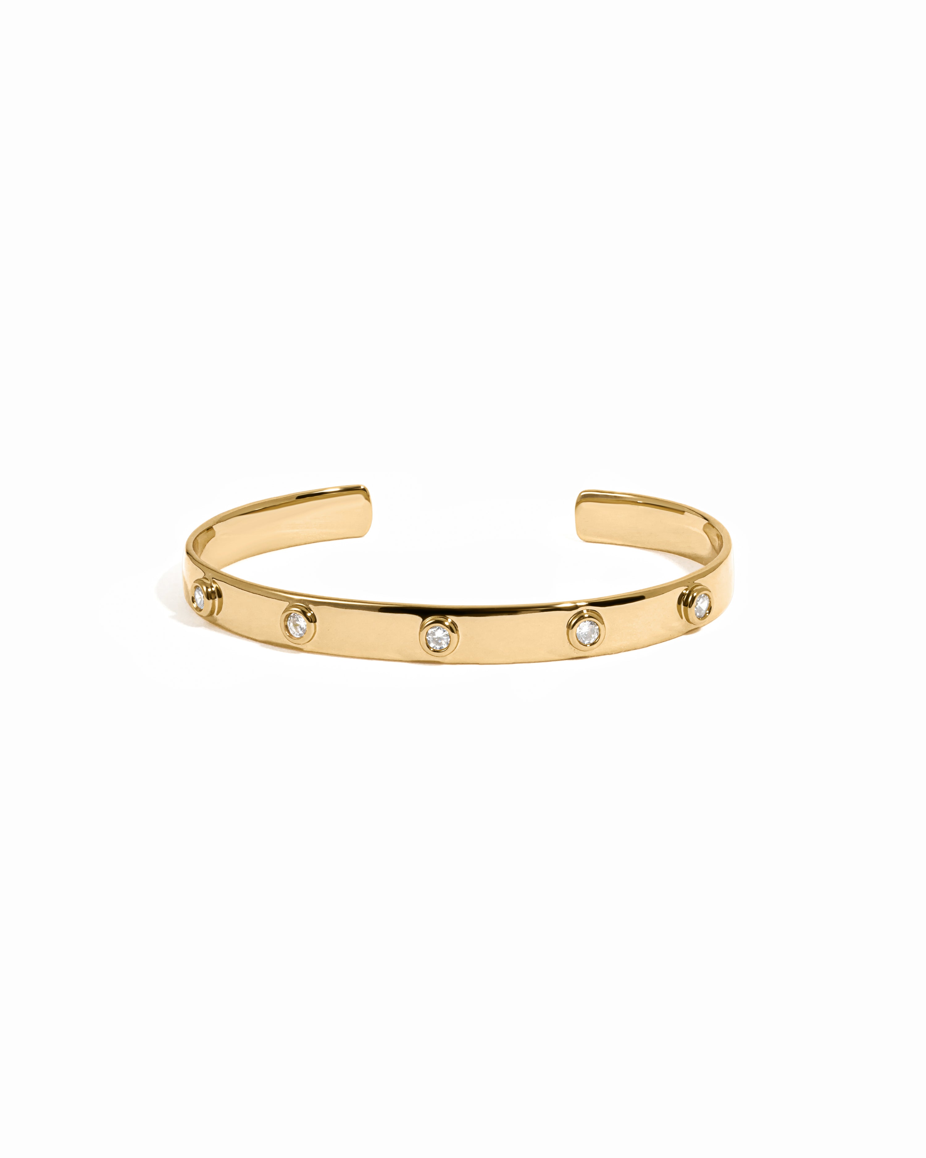 Gold cuff bracelet with small diamonds on a white background