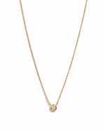 A super dainty, cubic zirconia bezel se necklace with a thin gold chain and a single cubic zirconia pendant.