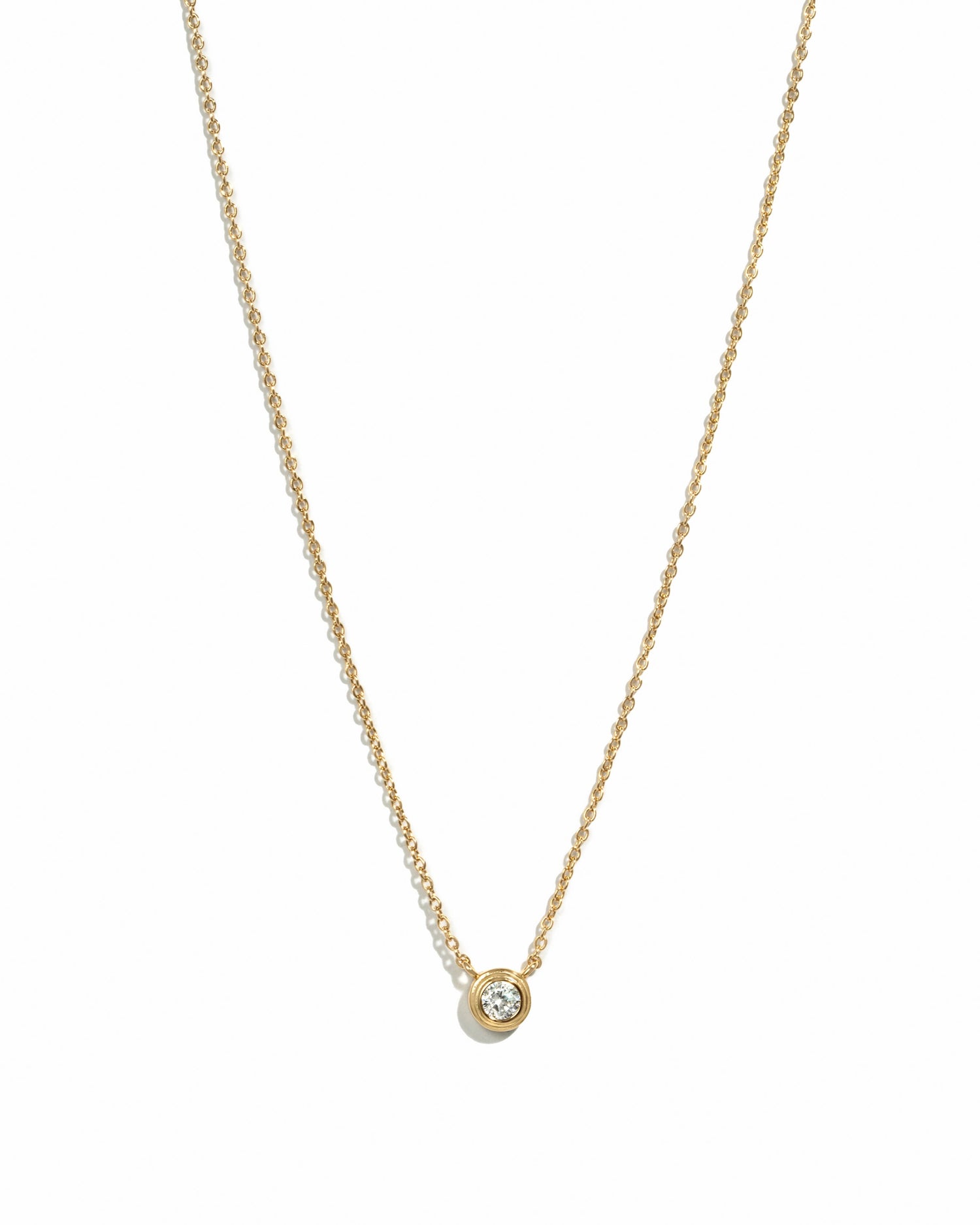 A super dainty, cubic zirconia bezel se necklace with a thin gold chain and a single cubic zirconia pendant.
