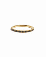 Gold eternity ring with black stones on a white background
