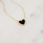 Close-up of the black onyx heart pendant, showcasing its shimmering pave diamond details on a thin gold chain.