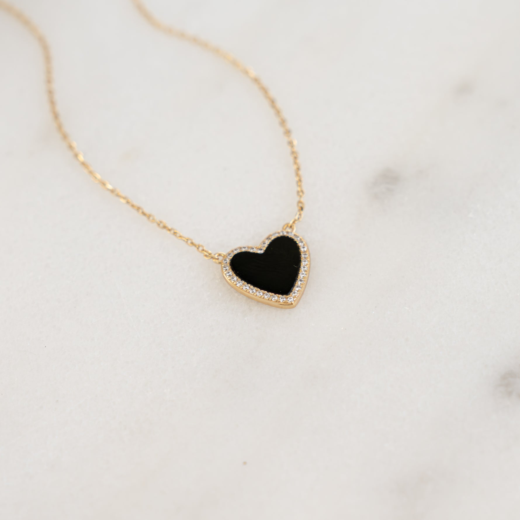 Close-up of the black onyx heart pendant, showcasing its shimmering pave diamond details on a thin gold chain.