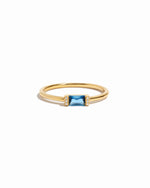 Gold ring with a blue gemstone on a white background
