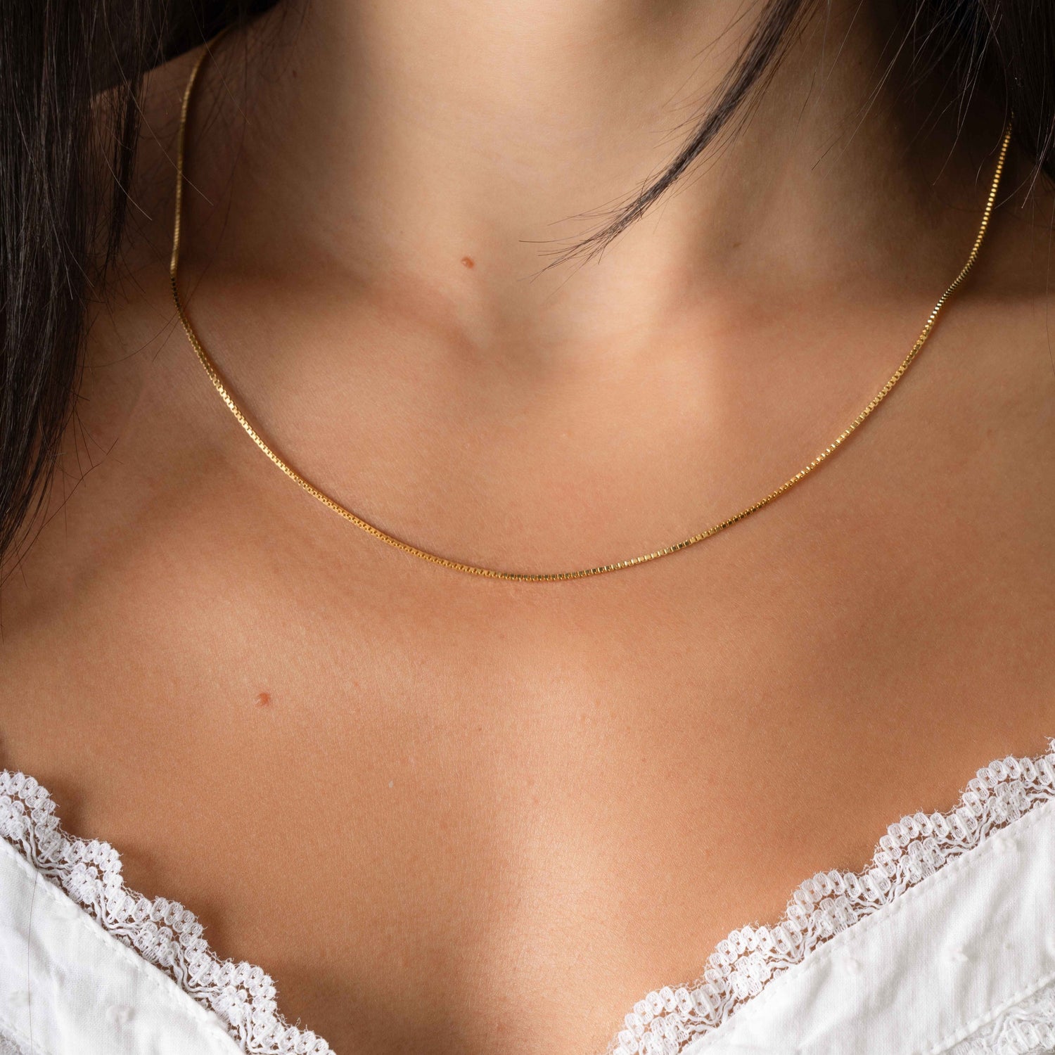 Model wearing dainty gold thin box chain necklace.