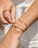 Model wearing celestial jewelry bracelet stack featuring a gold chain bracelet, a sun bracelet, and a cuff bracelet