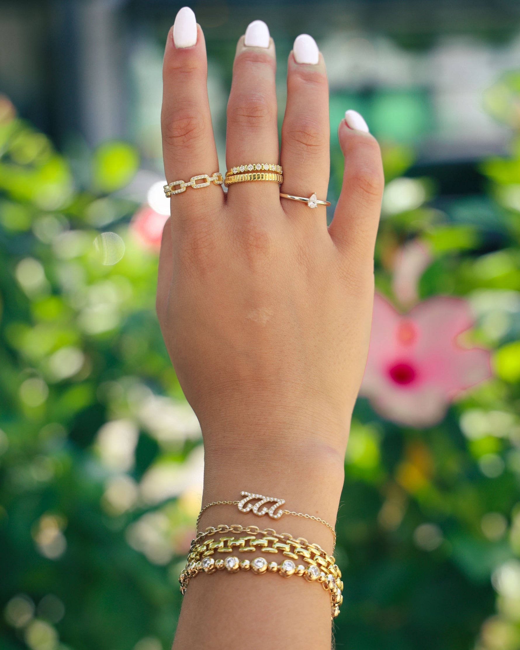 model wearing gold jewelry featuring a chain link bracelet, a 222 angel number bracelet, a small rolo chain bracelet and a big and little cz tennis bracelet 