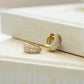 Closeup view of statement gold hoop earrings laying against book