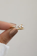 Closeup of hand holding Sami Jewels gold plated bypass spiral ring with 5 CZ diamonds