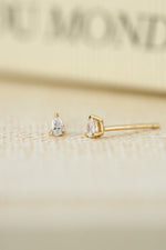 Gold tiny earrings on a blurred background