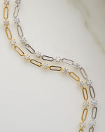 Gold chain and silver chain bracelet on plain background