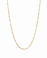 Gold chain beaded necklace on a white background