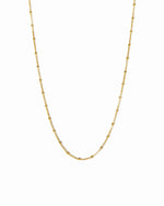 Close up image of gold simple beaded waist body chain on white background
