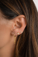 Model wearing gold celestial earrings featuring chain hoops, star stud earrings, and moon studs