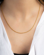 Gold chain dainty necklace on a person wearing a white shirt