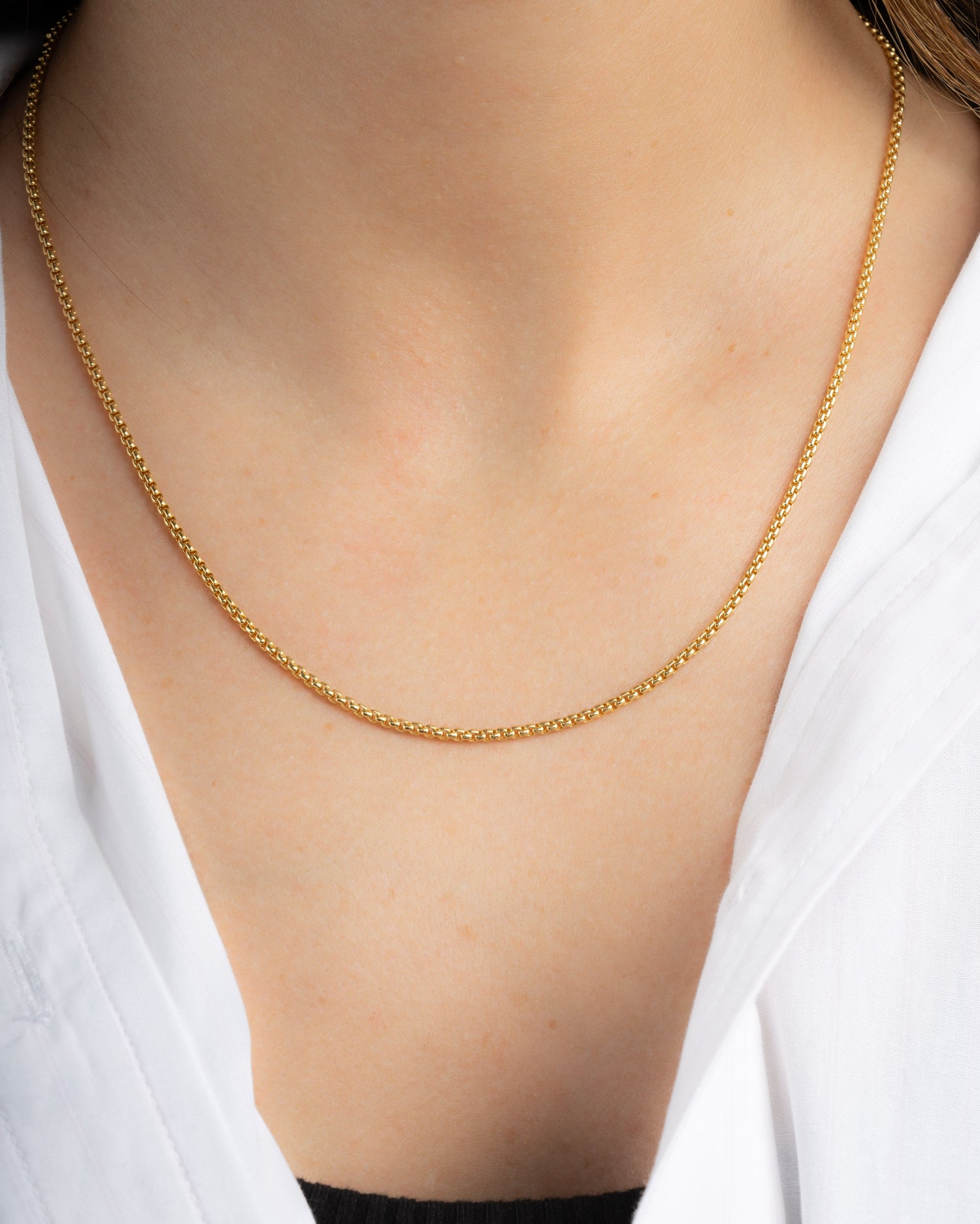 Gold chain dainty necklace on a person wearing a white shirt