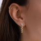 Model wearing tennis chain link earrings on the earlobe paired helix gold earrings.