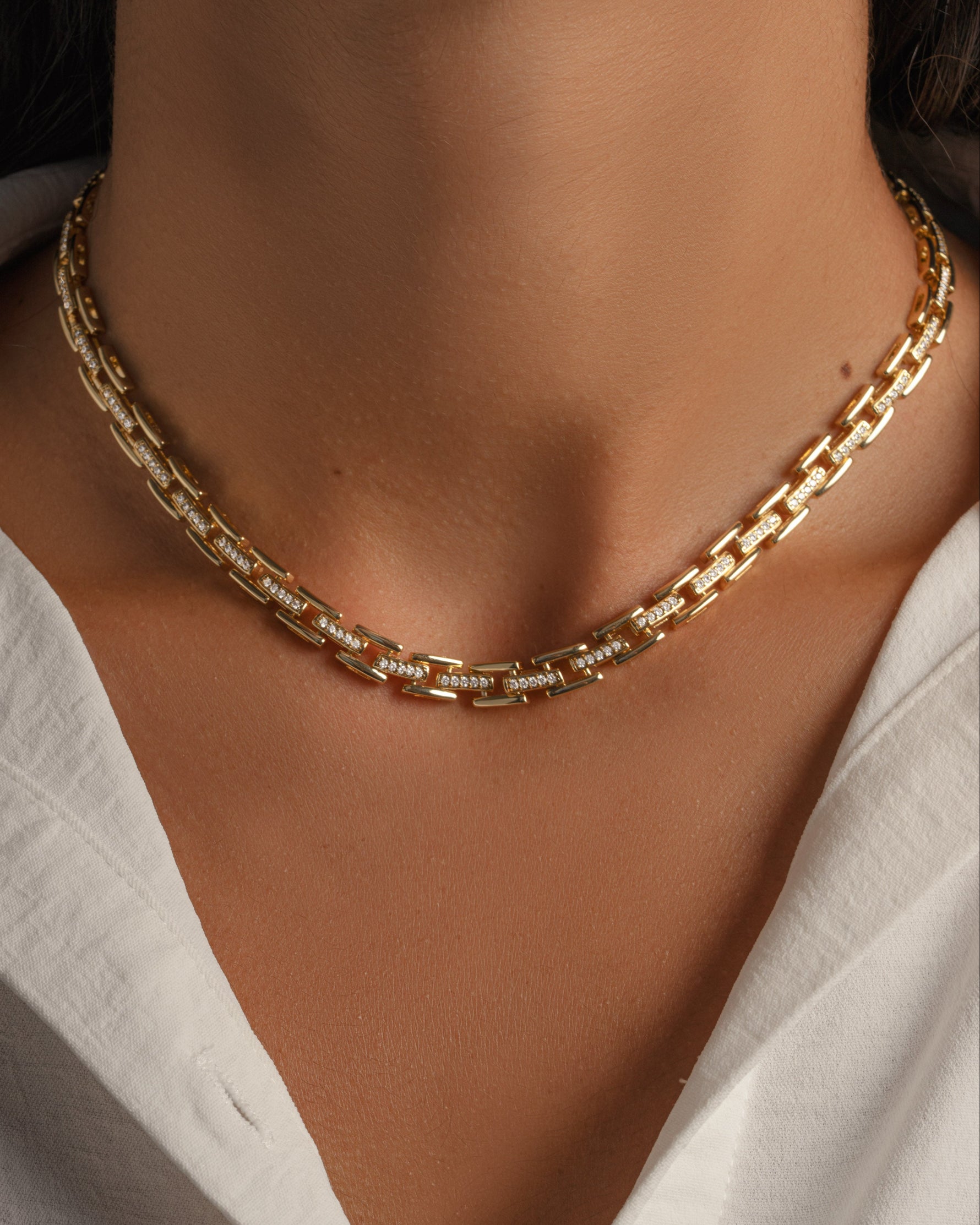 Model wearing gold chain necklace with cubic zirconia stones