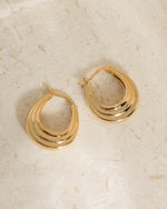 Pair of gold hoop earrings on a neutral background
