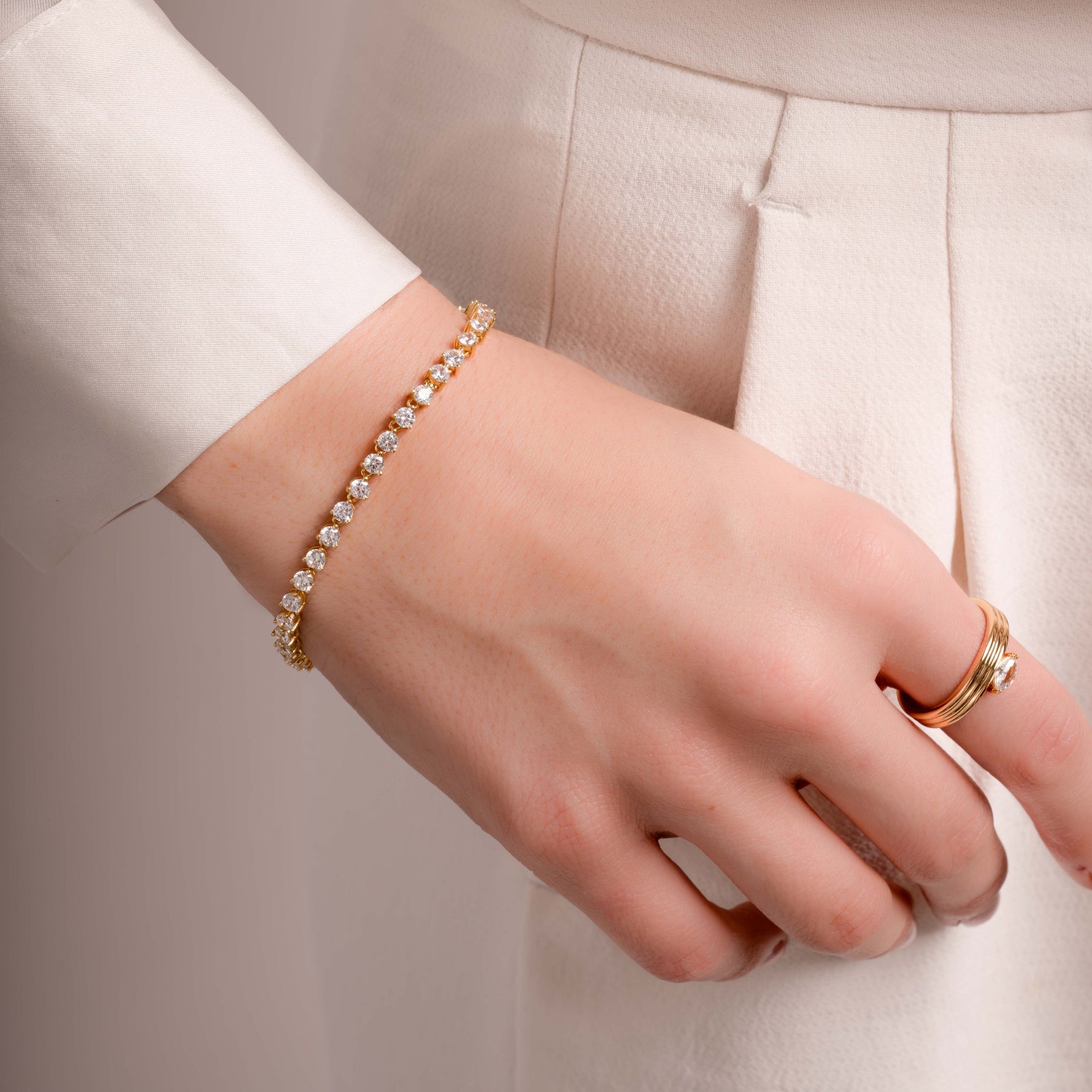 model wearing dainty gold jewelry featuring gold tennis bracelet 