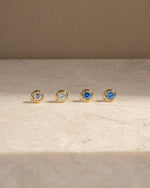 Gold stud earring on a marble background, one pair with cubic zirconia stone and one pair with march birthstone