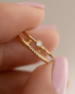 Gold boho toe ring being held between two fingers