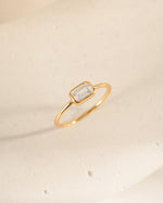 Gold cz ring with a baguette diamond on a beige background