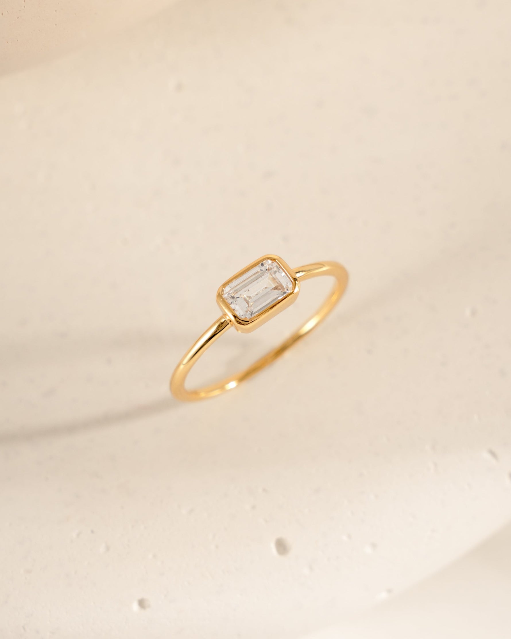 Gold cz ring with a baguette diamond on a beige background