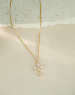Gold necklace with a cross pendant on a textured surface