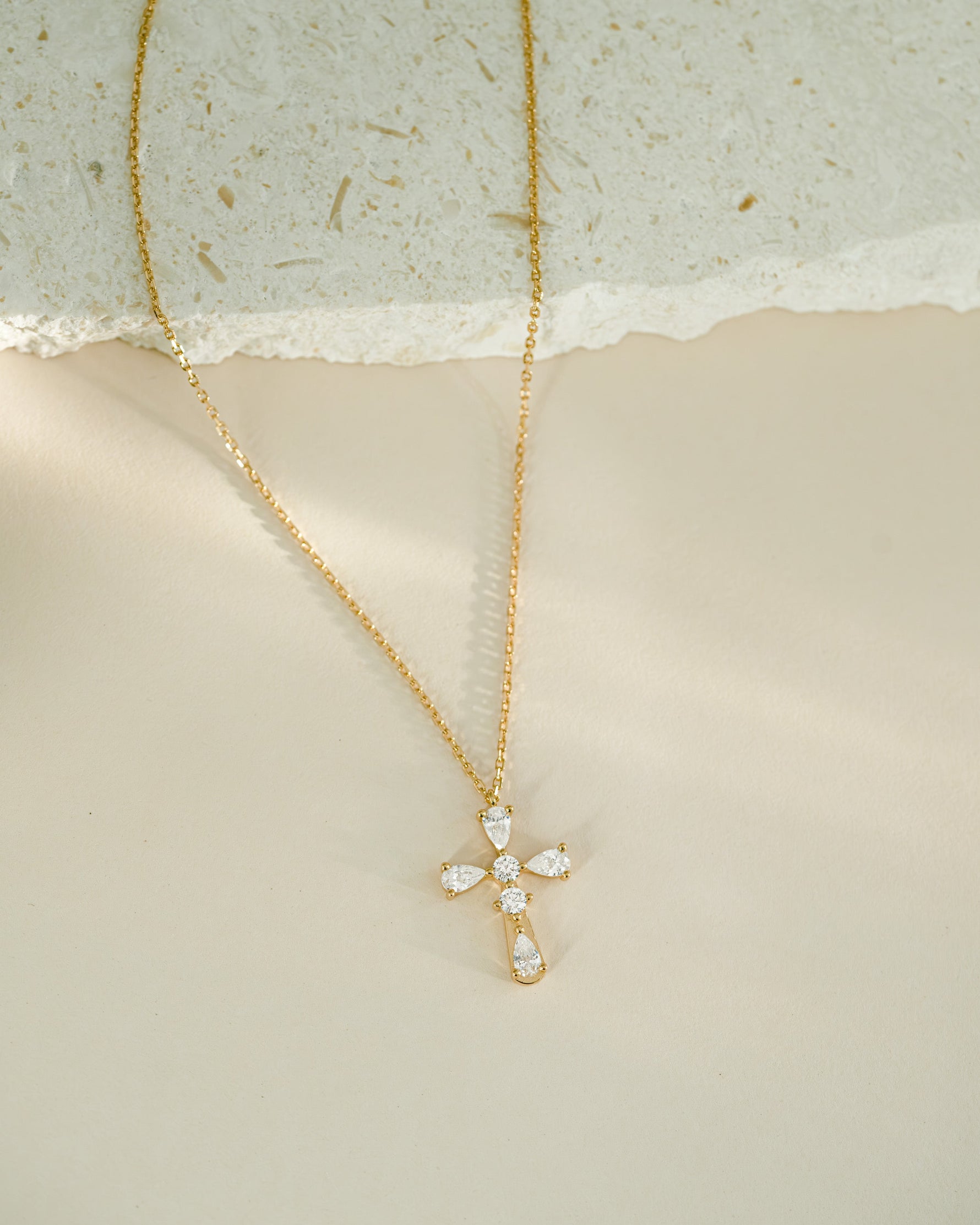 Gold necklace with a cross pendant on a textured surface