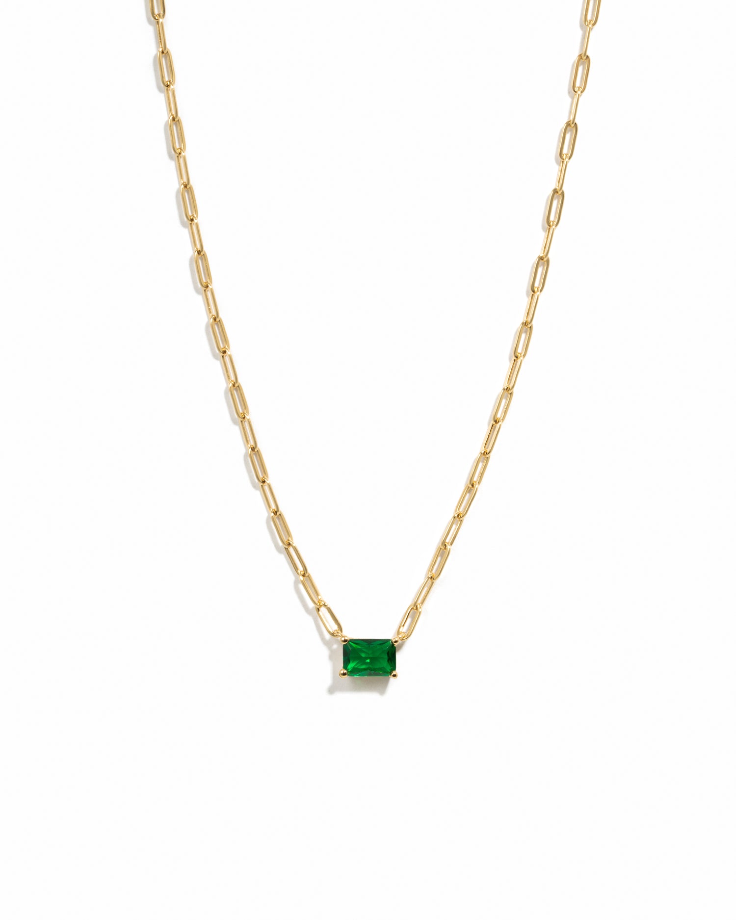 Gold necklace with a emerald pendant on a white background