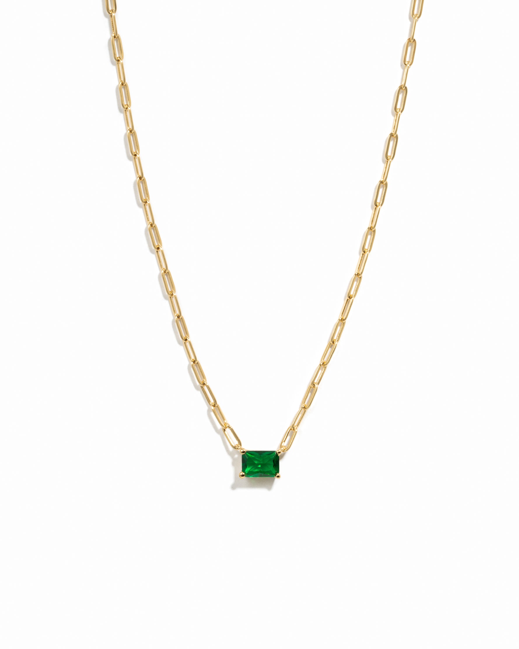 Gold necklace with a emerald pendant on a white background