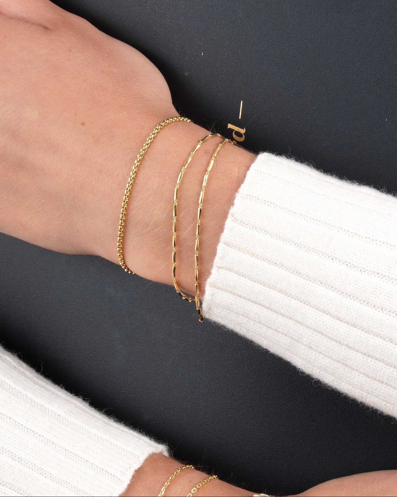 Model wearing gold chain bracelet stacks featuring a round box chain bracelet and a bracelet set