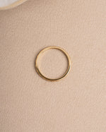 Gold minimalist ring on a beige textured surface