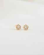 Gold cubic zirconia earrings with a flower earring design on a plain background