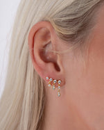 Model wearing gold ear climber earring with a dangling earring design