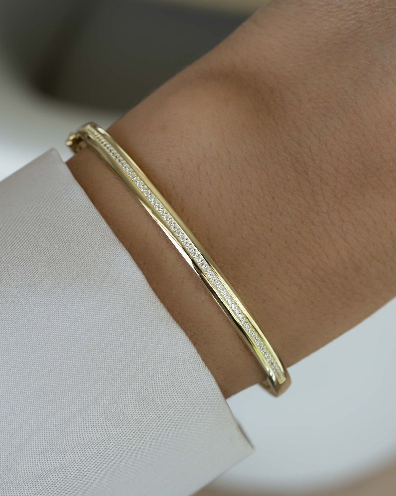 Model wearing minimalist gold bangle bracelet with cubic zirconia diamonds  
