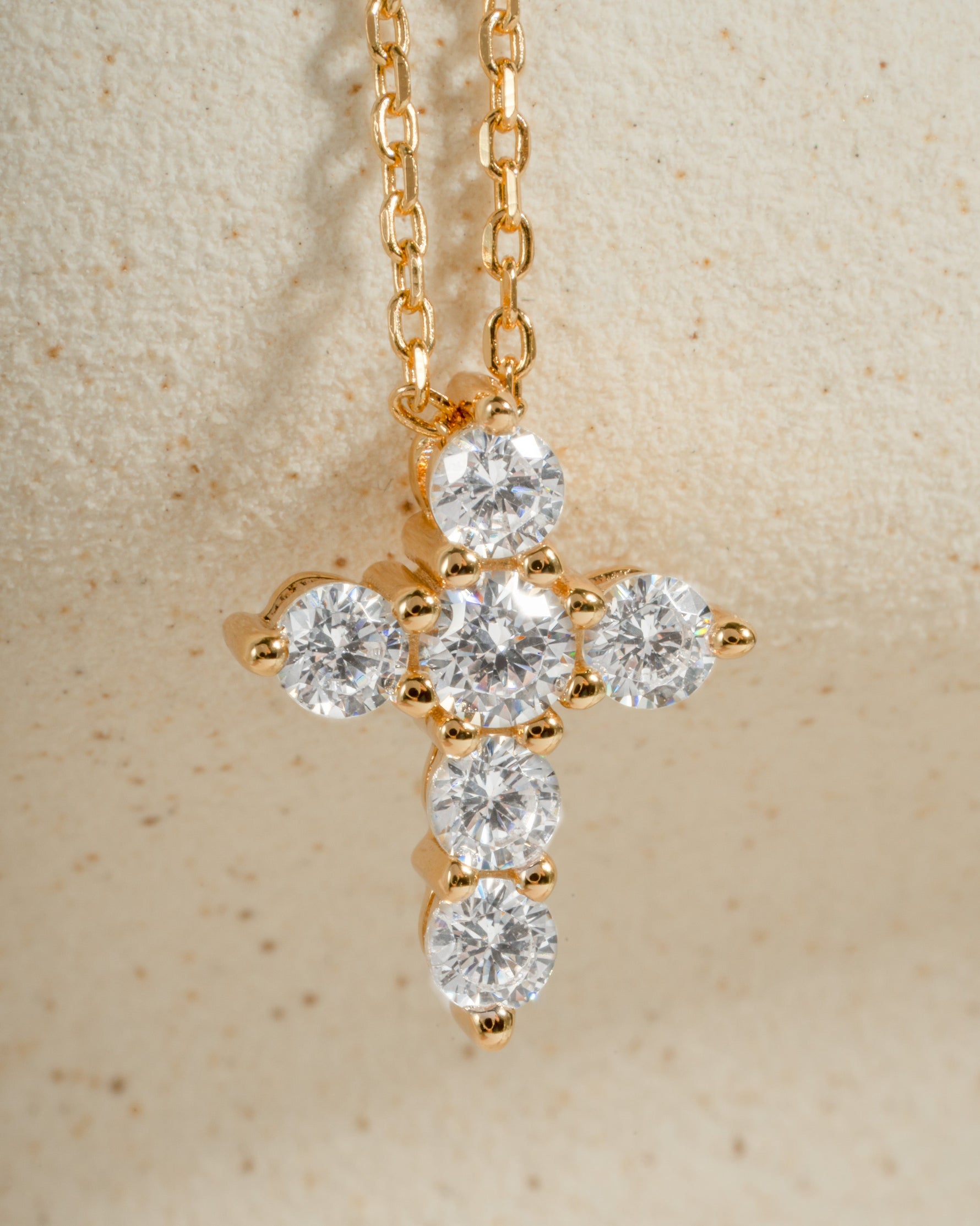 Gold chain dainty cross necklace on a beige background