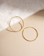 Flatlay of thin gold diamond hoops in 40mm, lightweight statement earrings crafted for daily wear.