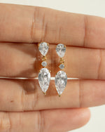 Gold bridesmaid earrings on the palm of a hand