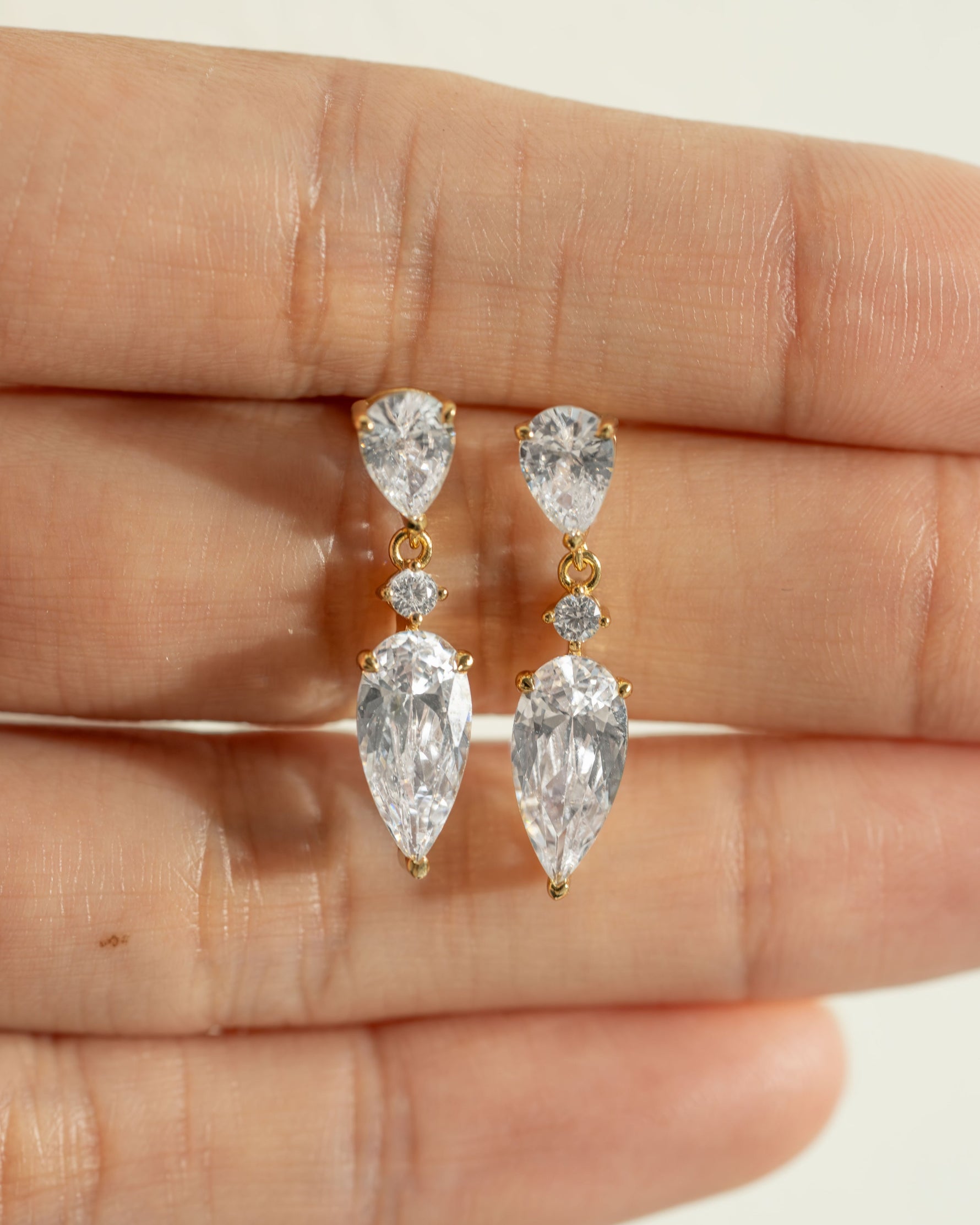 Gold bridesmaid earrings on the palm of a hand